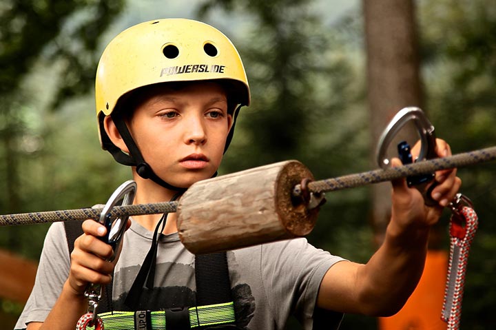 child with helmut attempting to use climbing equipment