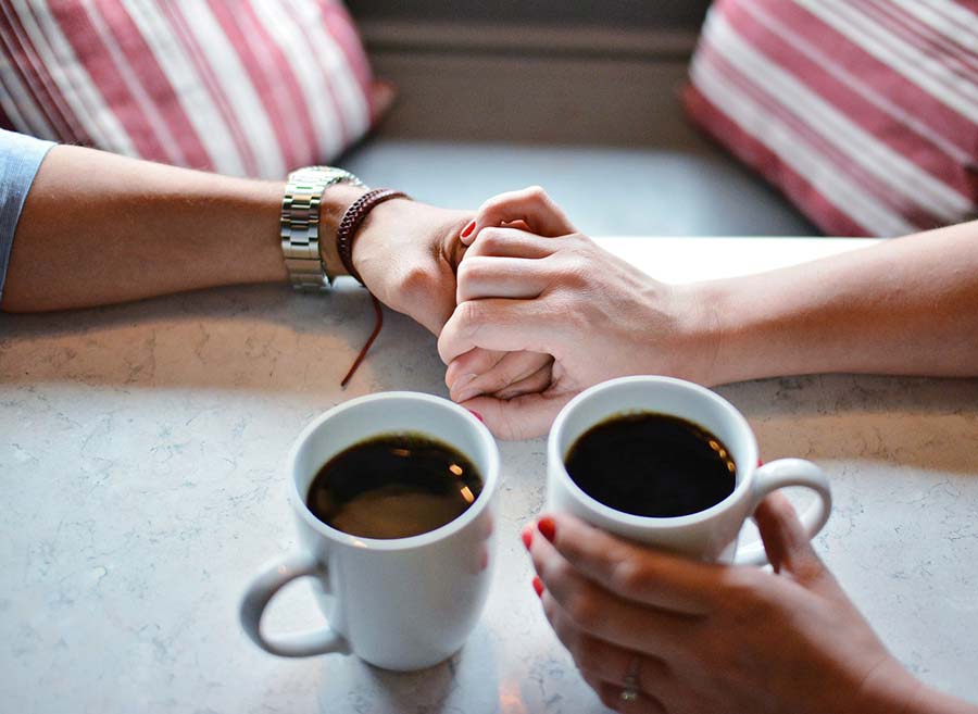 couple holding hands over a cup of coffee