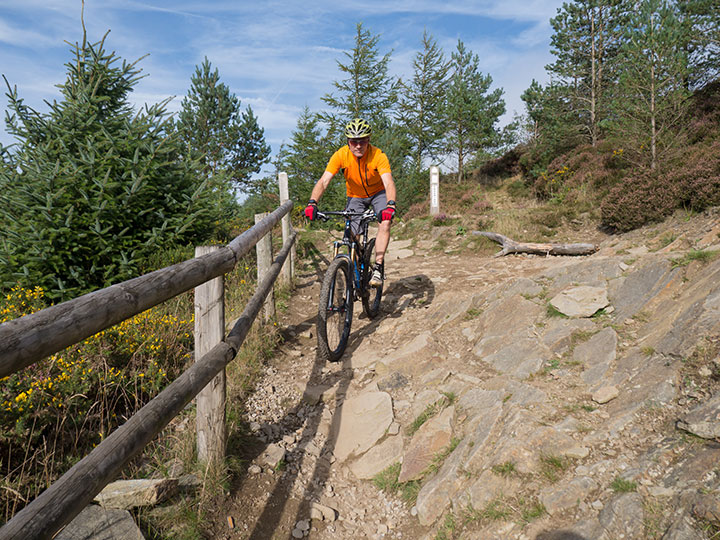 mountain biker cycling down a hill over tough terrain
