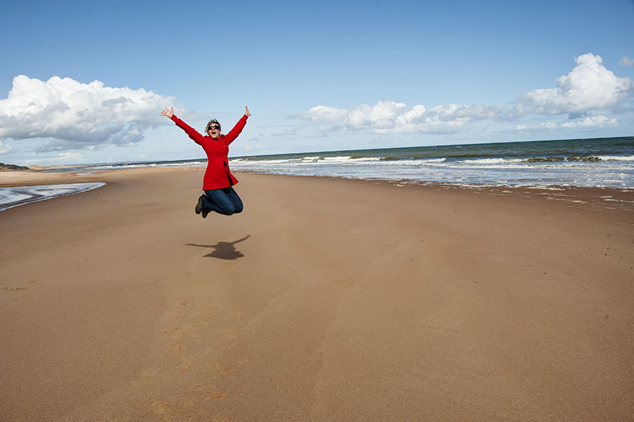Woman jumping for joy by the beach