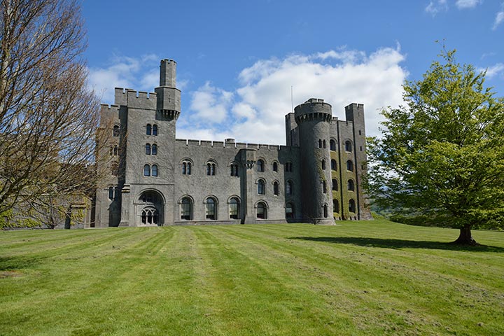 penrhyn castle with large lawn and trees in front
