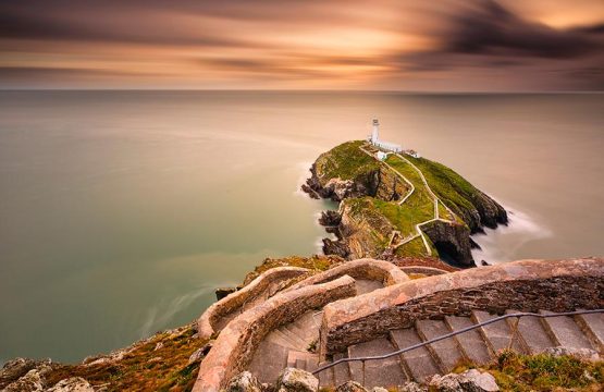 Lighthouse on coastal island with horizon and beautiful sunset at South Stack in Holyhead, North Wales. South Stack lighthouse at sunset overlooking the Irish Sea Isle of Anglesey